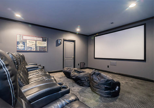 Remodeled basement with leather seats and a projection screen, an example of our Arlington interior renovation services.